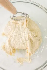 A bowl filled with focaccia bread dough being turned with a Danish Whisk - Hostess At Heart