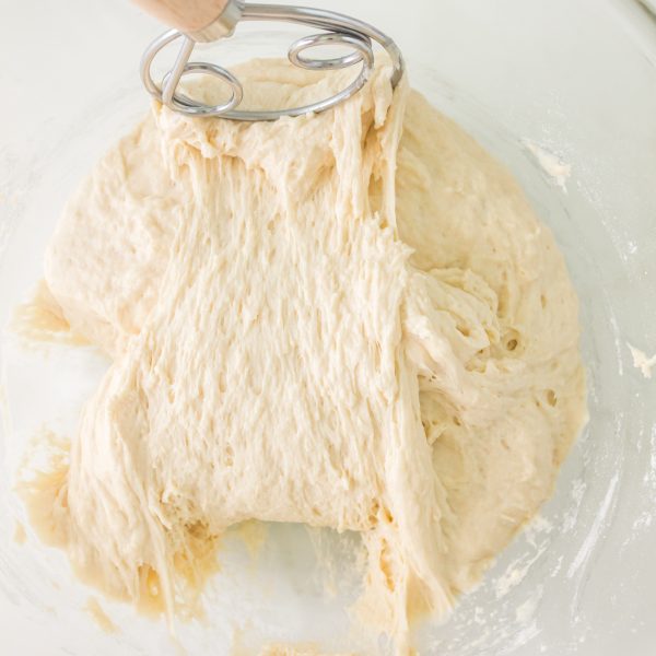 A bowl filled with focaccia bread dough being turned with a Danish Whisk - Hostess At Heart