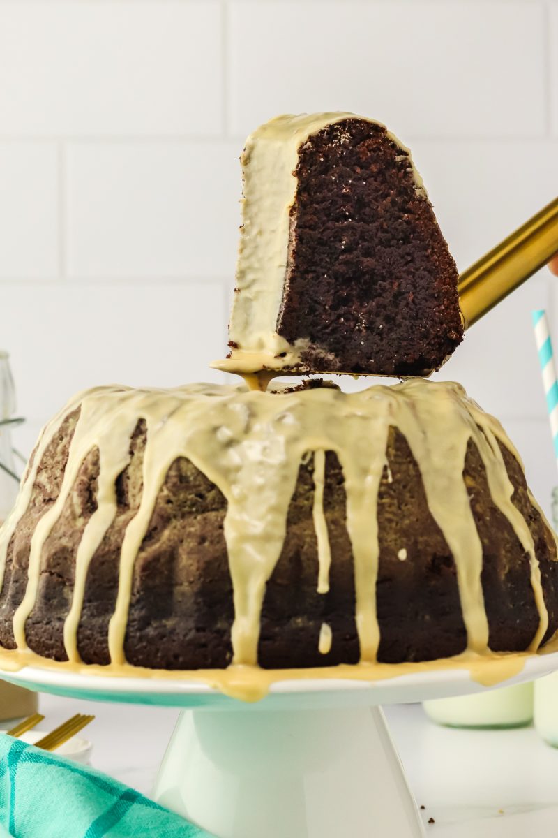 A slice of chocolate cake hovering over the glazed bundt cake - Hostess At Heart