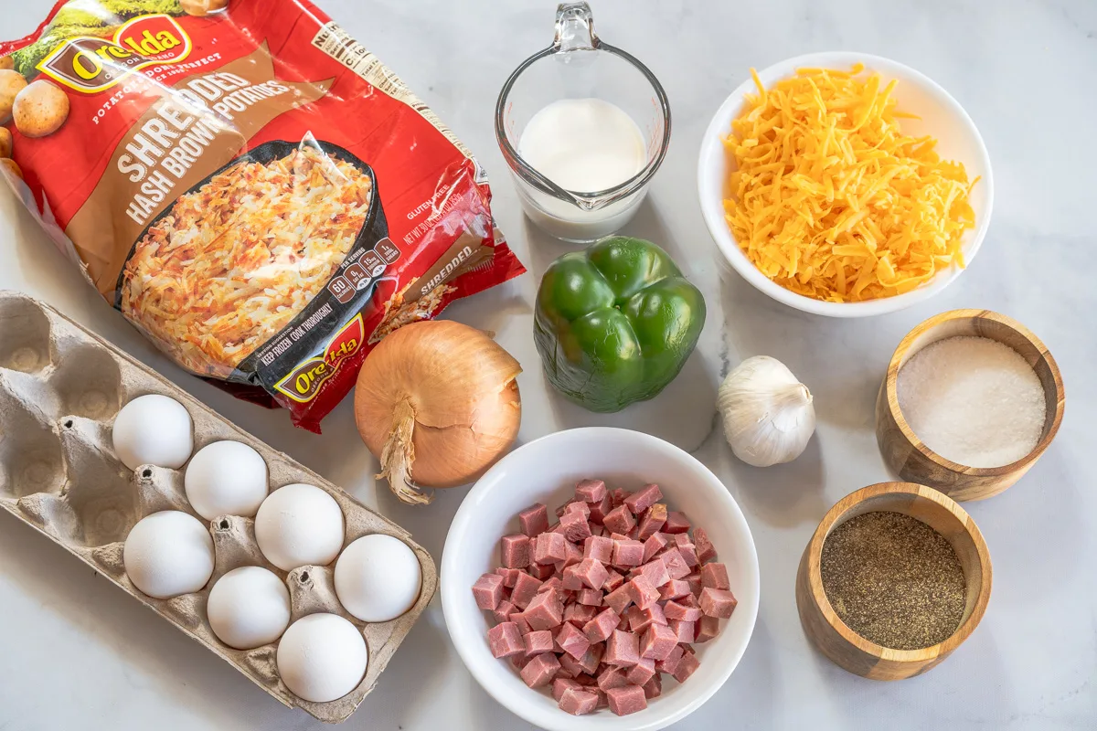 Ingredients for Corned Beef Casserole Recipe: shredded hashbrowns, milk, cheese, eggs, onions, green pepper, garlic, corned beef, salt and pepper.