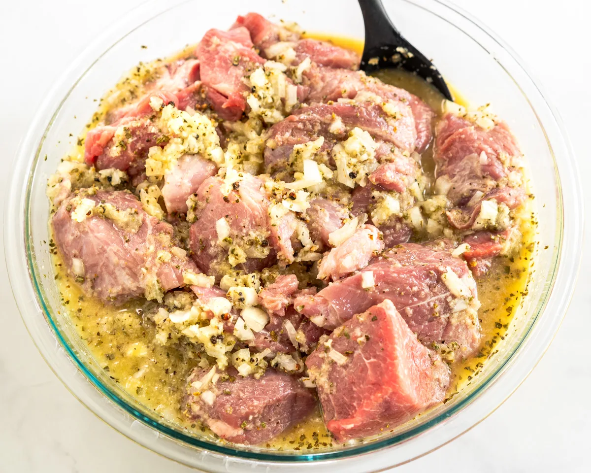 A mixing bowl containing chunks of pork in a Cuban mojo marinade. - Hostess At Heart