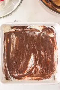 Baking dish filled with brownie batter thats filled with a cream cheese mixture - Hostess At Heart
