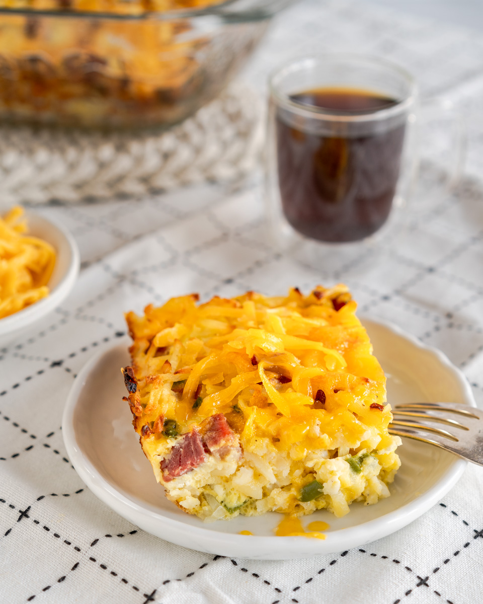 Sideview of a slice of breakfast casserole made with corned beef, shredded potatoes, cheese, and vegetables - Hostess At Heart