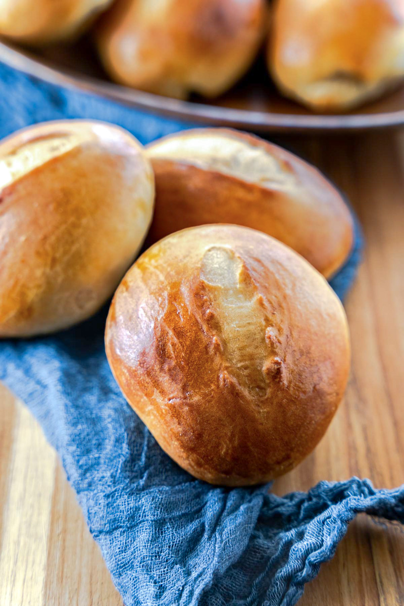 Three golden browned baked Cuban Bread Rolls sitting on a cutting board - Hostess At Heart