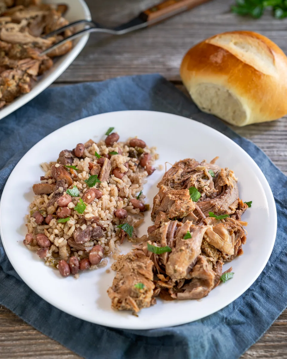 Shredded Cuban Roast Pork on a plate next to a serving of Red Beans and Rice garnished with parsley - Hostess At Heart