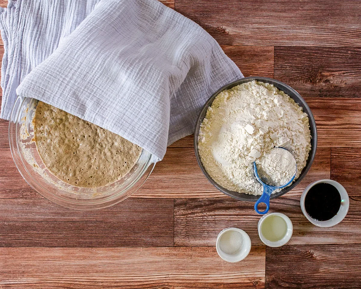 Ingredients used to make Pumpernickle sourdough bread including a sourdough sponge, flour, molasses, salt, and oil.