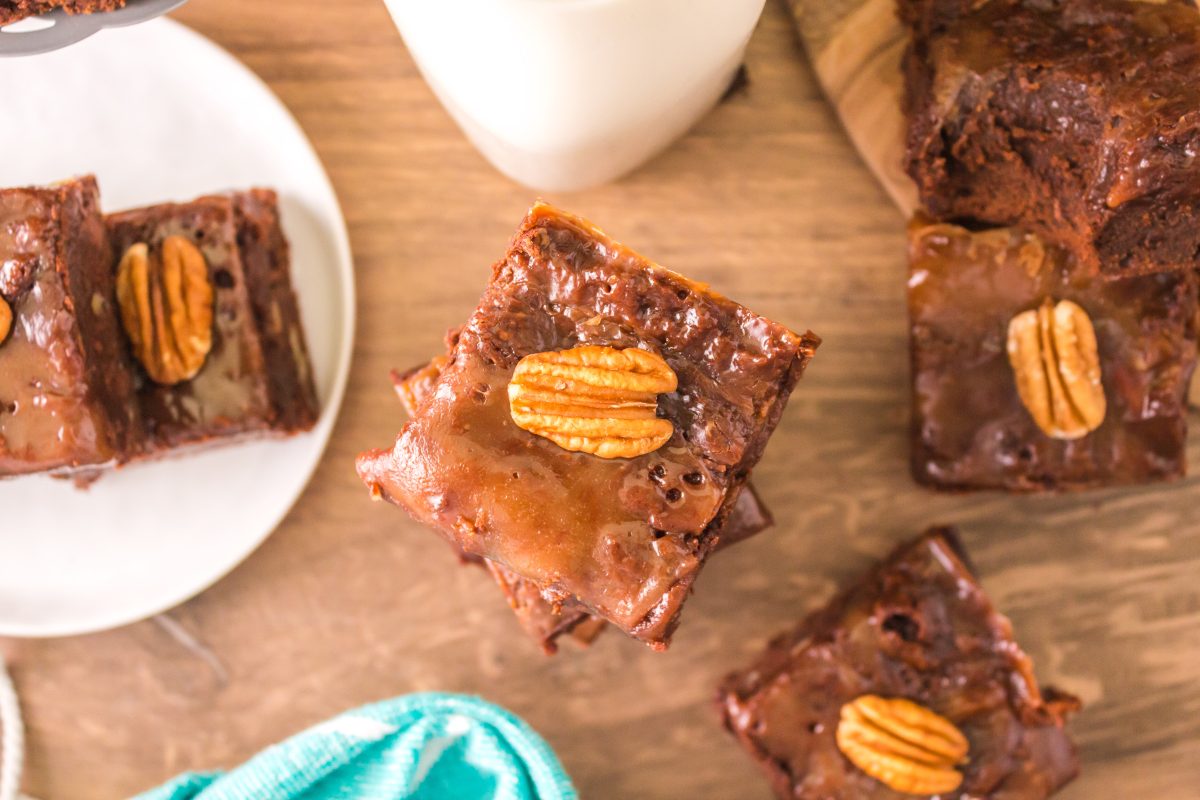 Top down view of chocolate brownies topped with caramel and a pecan - Hostess At Heart