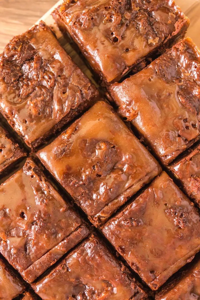 Close up of sliced chocolate Brownies topped with caramel on a cutting board. Hostess At Heart