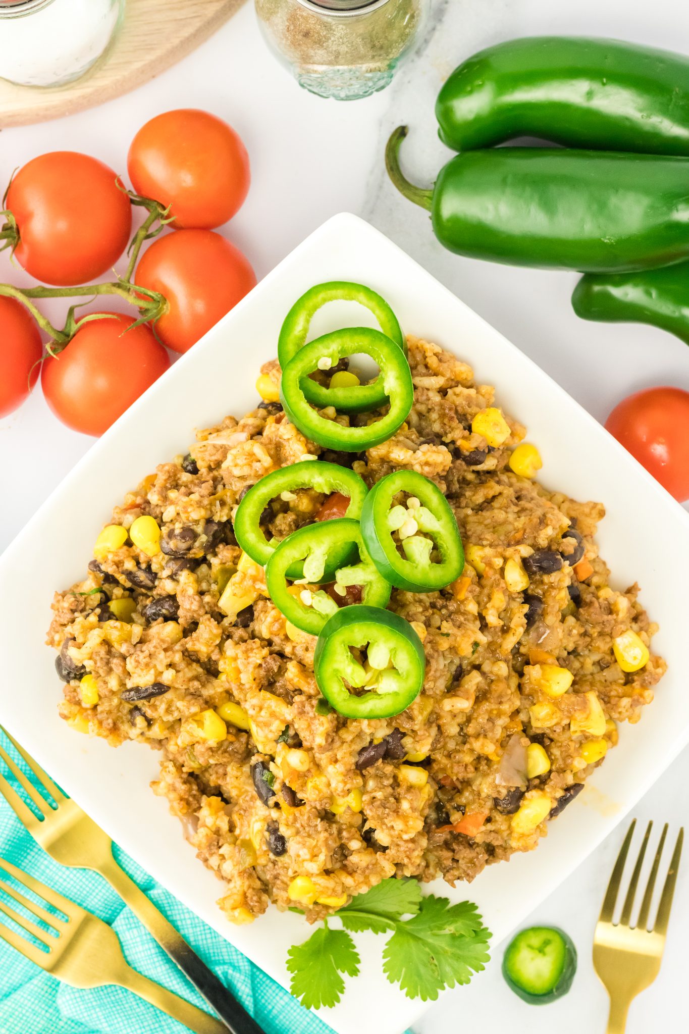 Top down view of a white dish filled with dirty rice garnished with slices of fresh jalapenos - Hostess At Heart