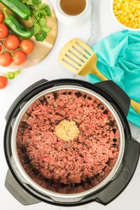 Ground beef and spices in an instant pot for a dirty rice with ground beef recipe- hostess at heart