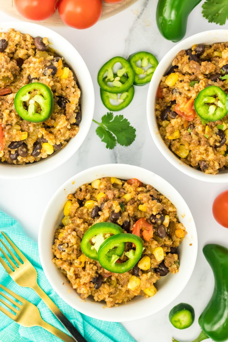 Top down view of bowls filled with creole rice loaded with beans, ground beef, and corn, topped with fresh jalapenos - Hostess At Heart