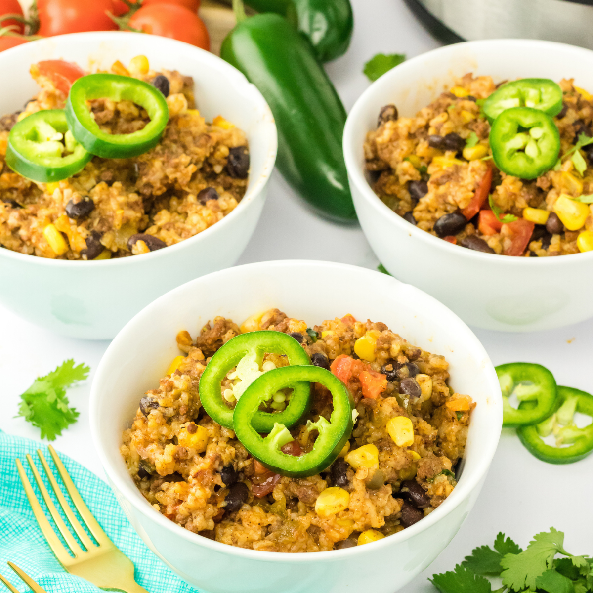 Top down view of three bowls filled with cajun rice garnished with slices of jalapenos - Hostess At Heart