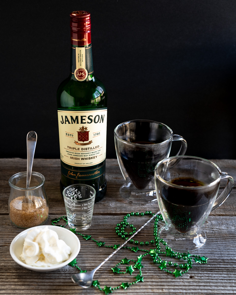 Ingredient image including two cups of hot coffee, Jameson whiskey, turbinado sugar, and whipped topping.