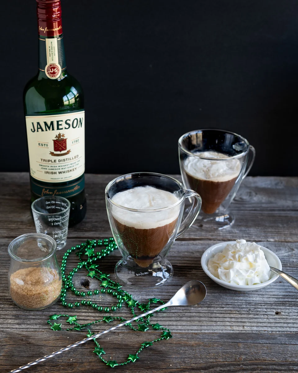 Angled view of two cups of Irish Coffee topped with whipped topping