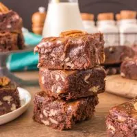 A sideview of three pieces of turtle fudge brownies stacked on top of each other showing moisture and texture - Hostess At Heart