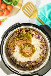 Top down view of an instant pot filled with ground beef, red onion, carrots, seasoning and rice before it's cooked - Hostess At Heart