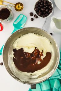 Top down view of a mixing bowl filled with cream cheese filling and a chocolate cocoa mix.
