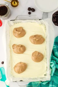 A baking dish filled with a creamy cheesecake filling over an Oreo crust and topped with dollops of a creamy cappuccino filling. Hostess At Heart