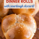 Top down view of a baked cloverleaf dinner roll brushed with butter and sprinkled with sea salt - Hostess At Heart