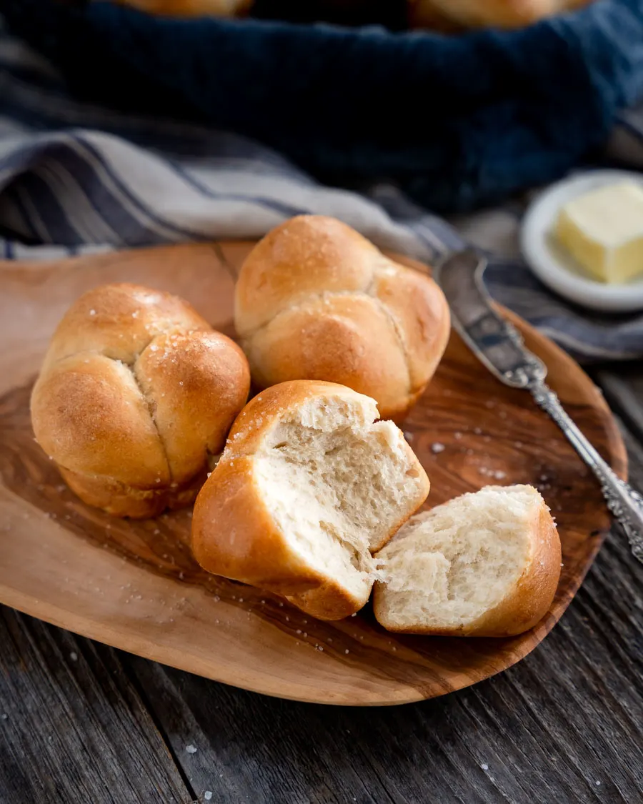 3 Sour dough cloverleaf rolls on a platter with the piece of on roll torn off showing a soft tender crumb - Hostess At Heart