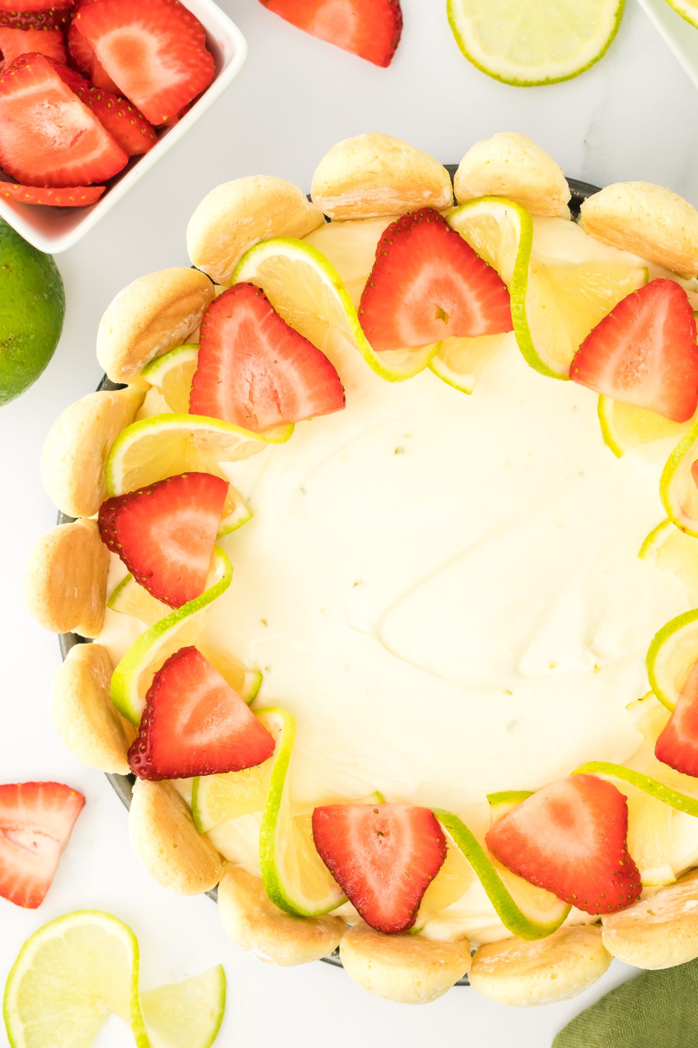 Top down close up of no bake lime cheesecake topped with strawberries and lime slices.