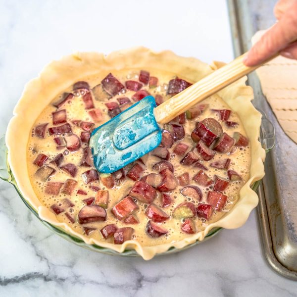 A pie plate covered with a bottom pie crust and filled with a rhubarb custard filling - Hostess At Heart