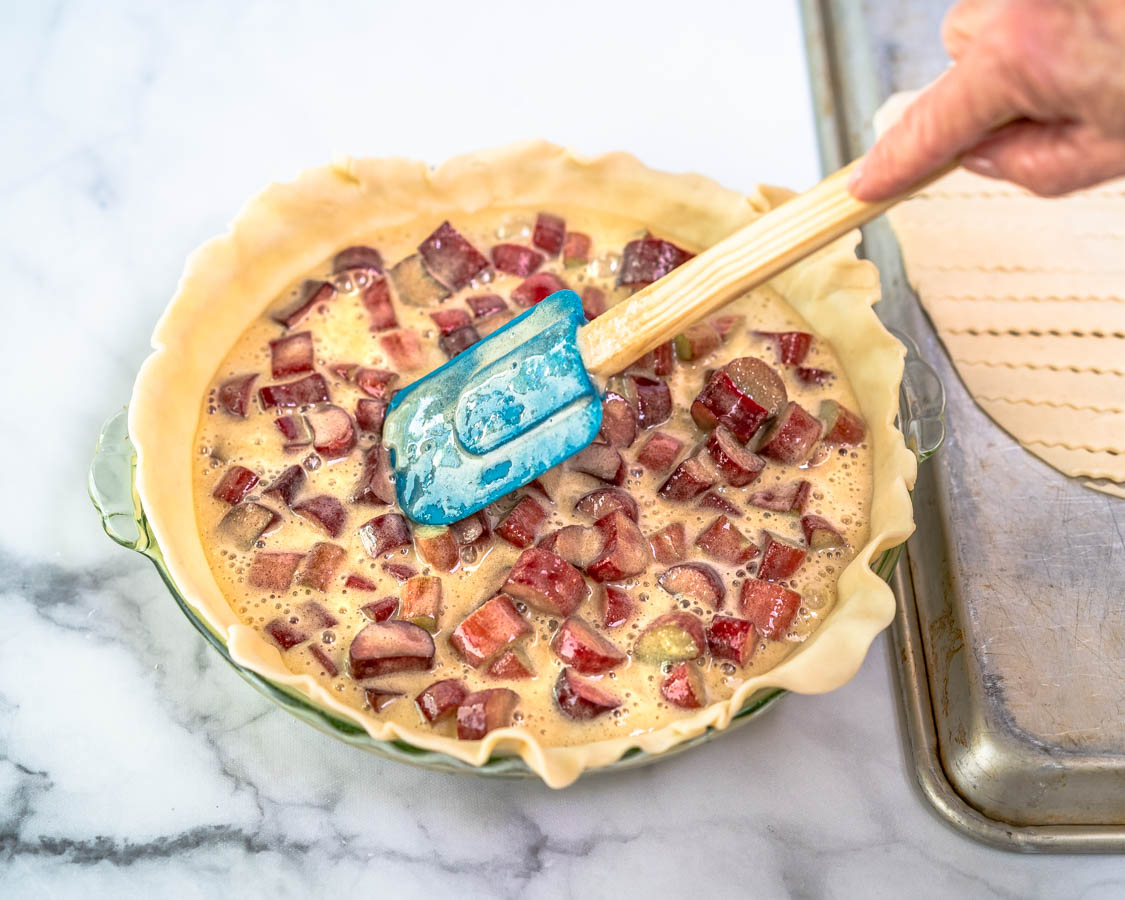 A pie plate covered with a bottom pie crust and filled with a rhubarb custard filling - Hostess At Heart