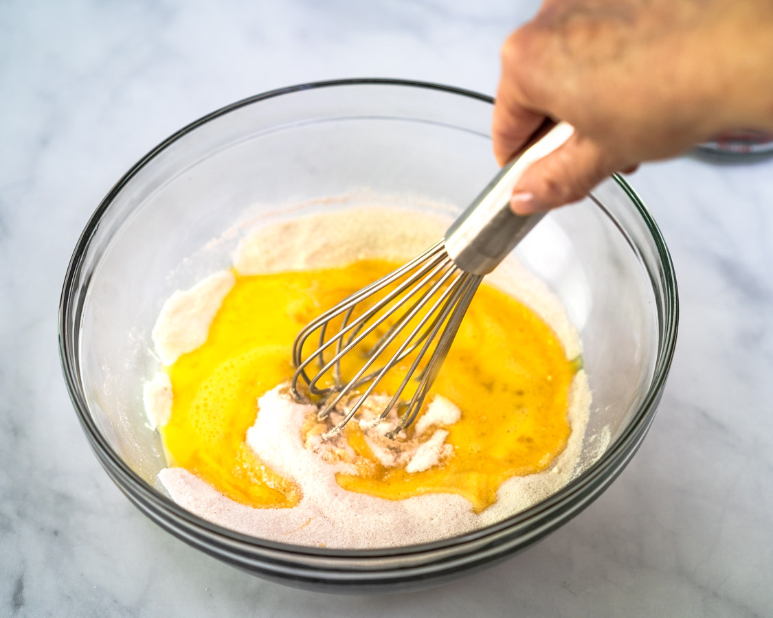 Beaten eggs being mixed into the dry ingredients in a bowl to make rhubarb custard pie filling. Hostess At Heart