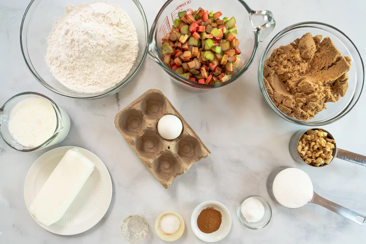 Ingredients for the Old fashioned rhubarb cake recipe: flour, rhubarb brown sugar, milk, vinegar, egg, shortening, salt, baking soda, walnuts, sugar, and ground cinnamon.
