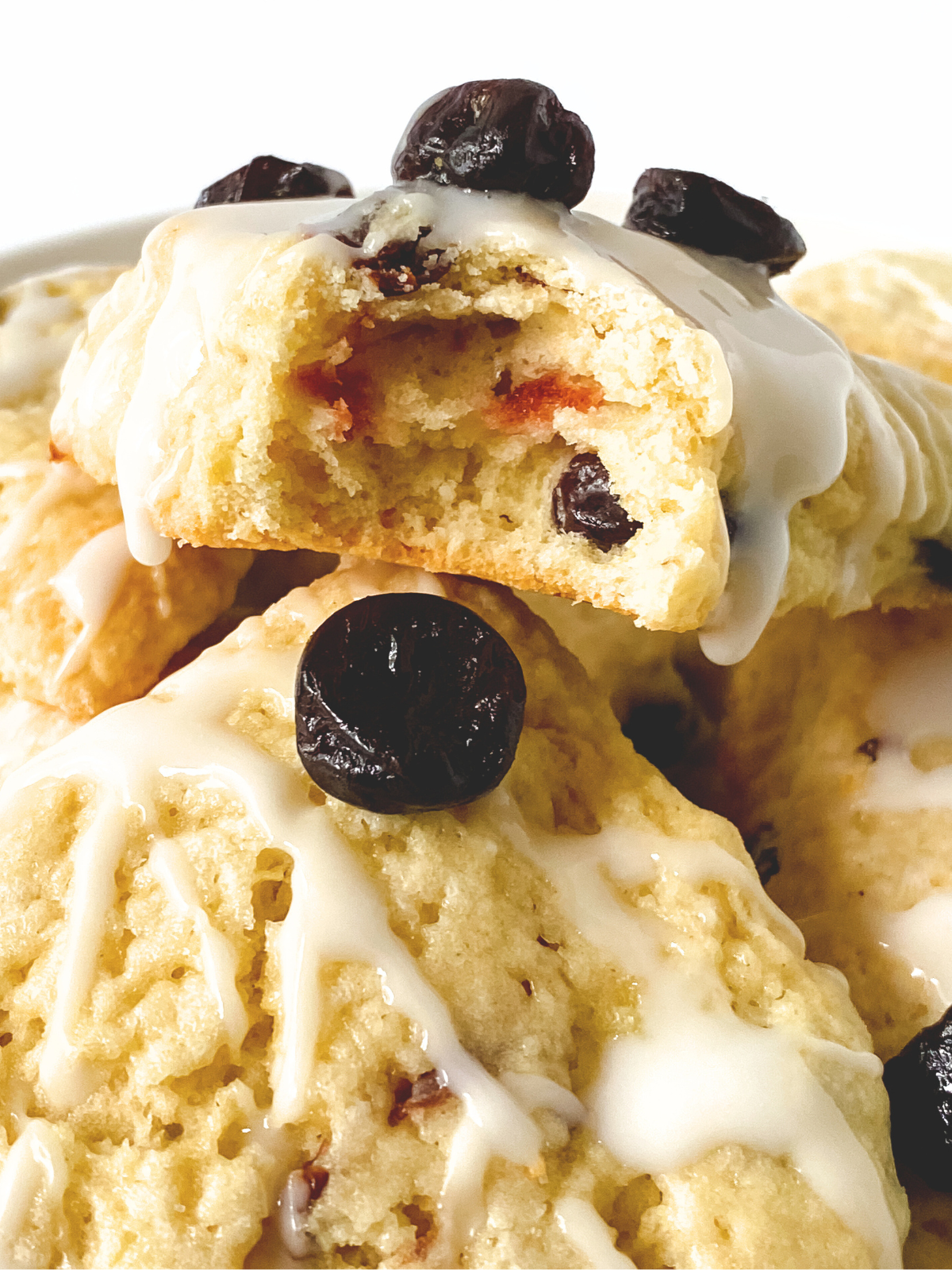 Front view of baked Cherries scones with a bite taken out of the top one showing a moist tender crumb.