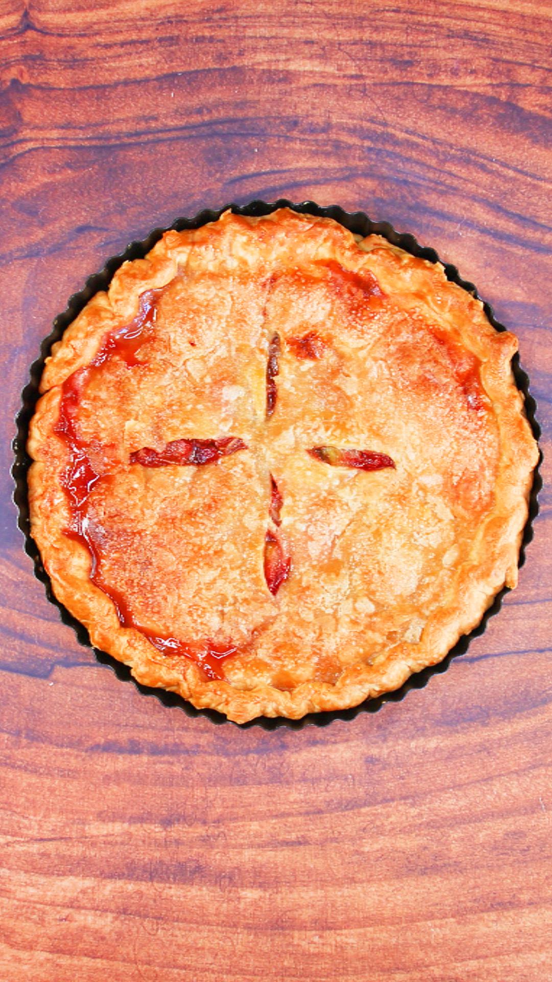 Top down view of a baked two crust rhubarb strawberry pie with juices pooling over the top edge - Hostess At Heart