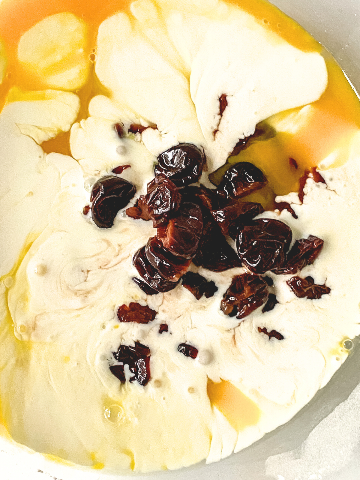 Wet scones ingredients combined in a mixing bowl including eggs, whipping cream, vanilla, and drained cherries. Hostess At Heart
