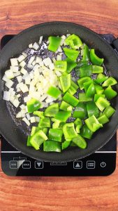 A skillet containing diced onion and chopped poblano peppers - Hostess At Heart