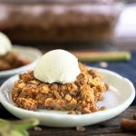 Sideview of a serving of rhubarb dessert topped with oat crunch topping and a scoop of ice cream - Hostess At Heart