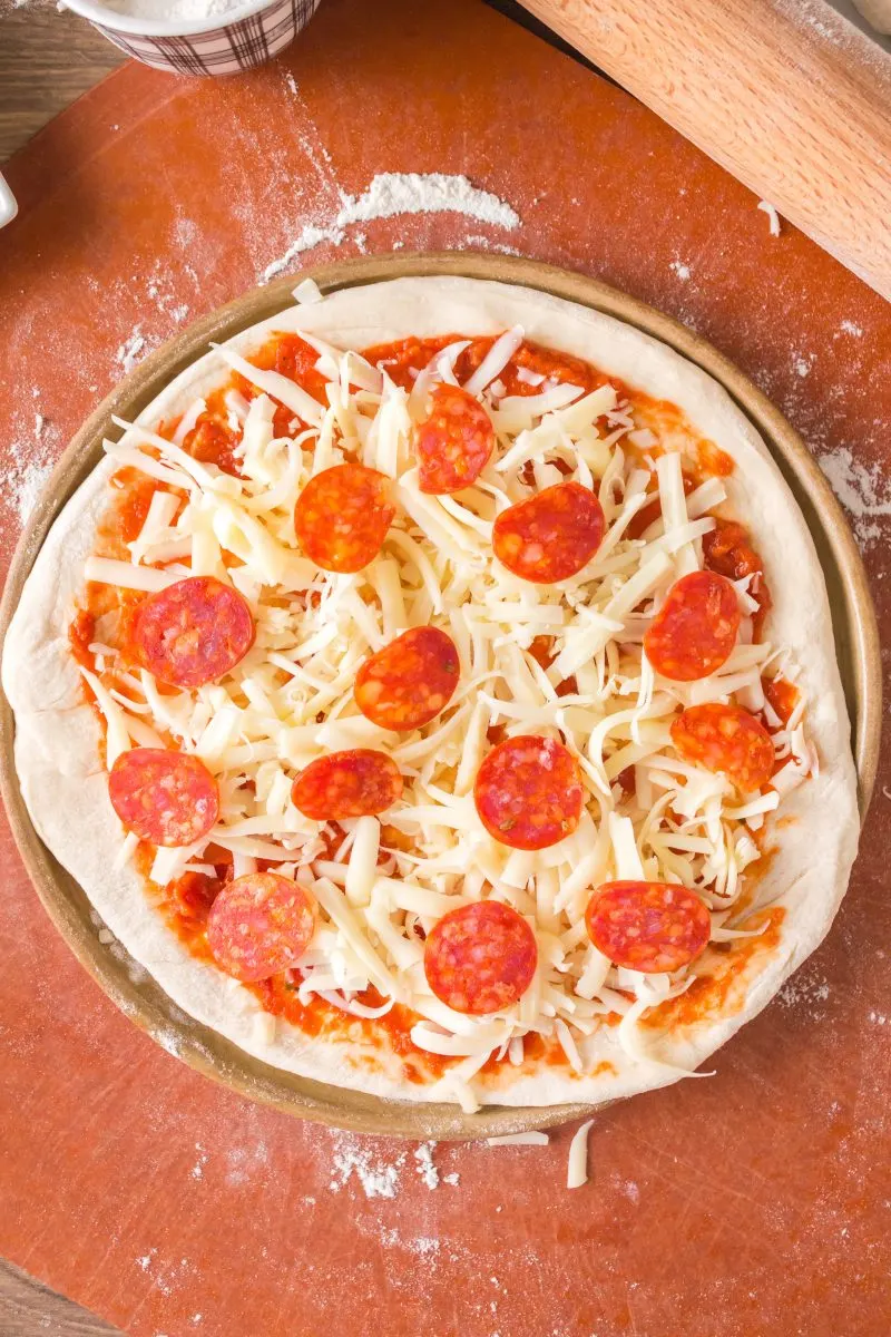 Top down view of a homemade pizza topped with cheese and pepperoni - Hostess At Heart