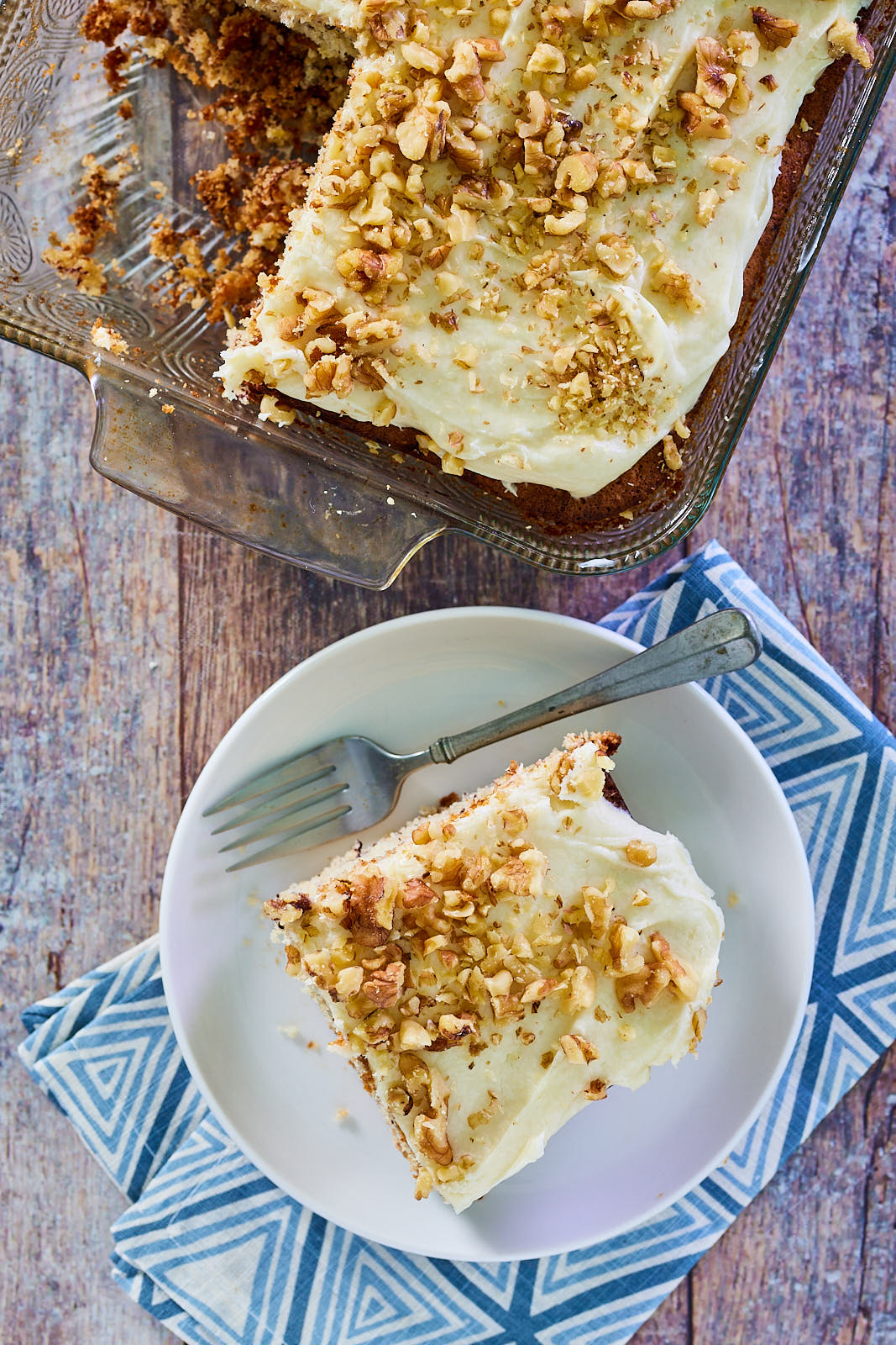 Top down view of a slice of cake frosted and garnished with chopped walnuts - Hostess At Heart