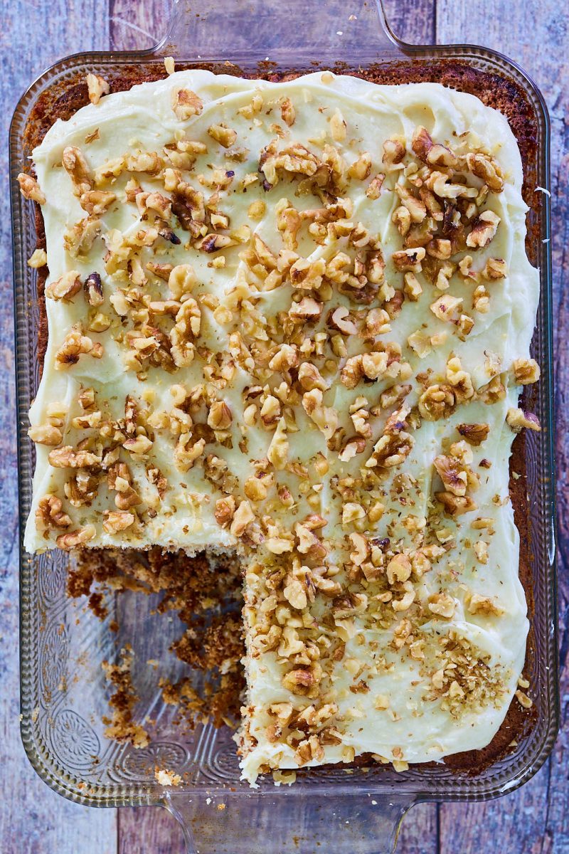 Top down view of a baked cake topped with frosting and chopped walnuts - Hostess At Heart