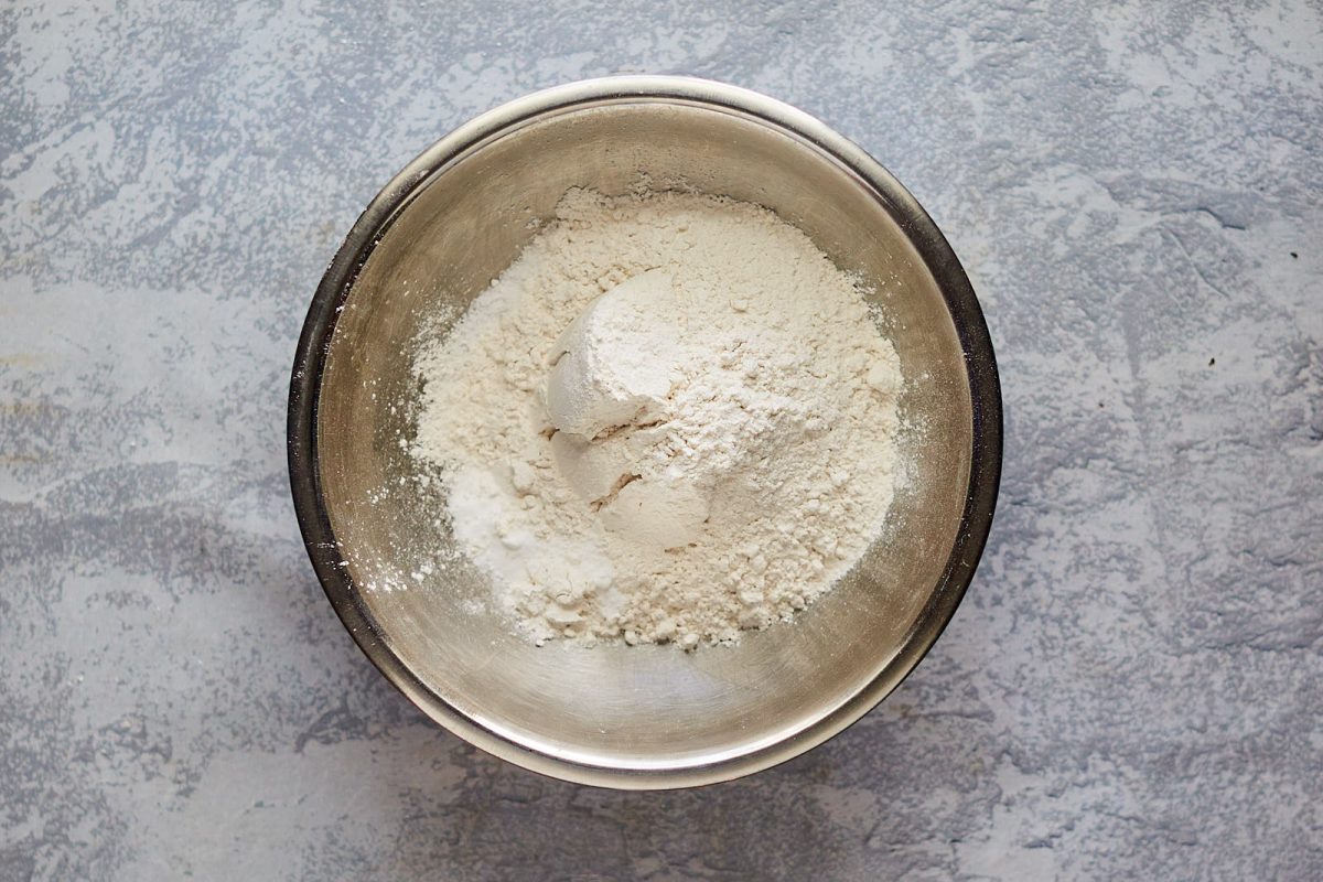 A mixing bowl containing flour, baking powder, baking soda and salt. Hostess At Heart