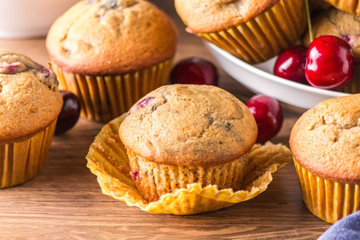 Side view of golden brown baked muffins loaded with cherries - Hostess At Heart