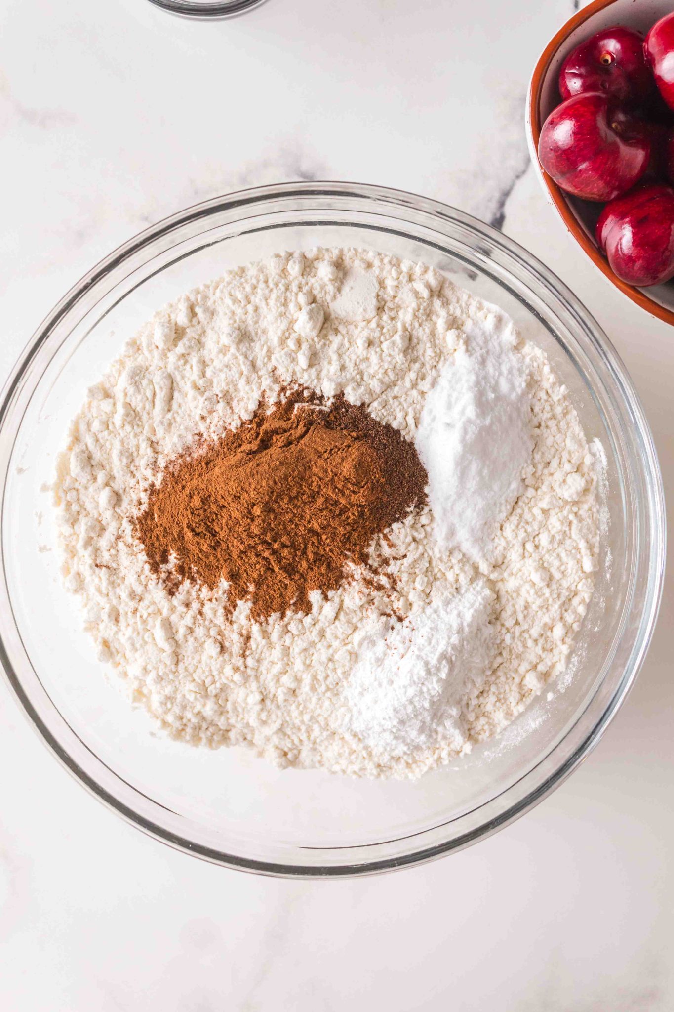 A mixing bowl filled with dry ingredients including flour, cinnamon, alspice, salt and baking soda. Hostess At Heart