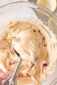 A scoop filled with cherry muffin batter hovering over the bowl - Hostess At Heart