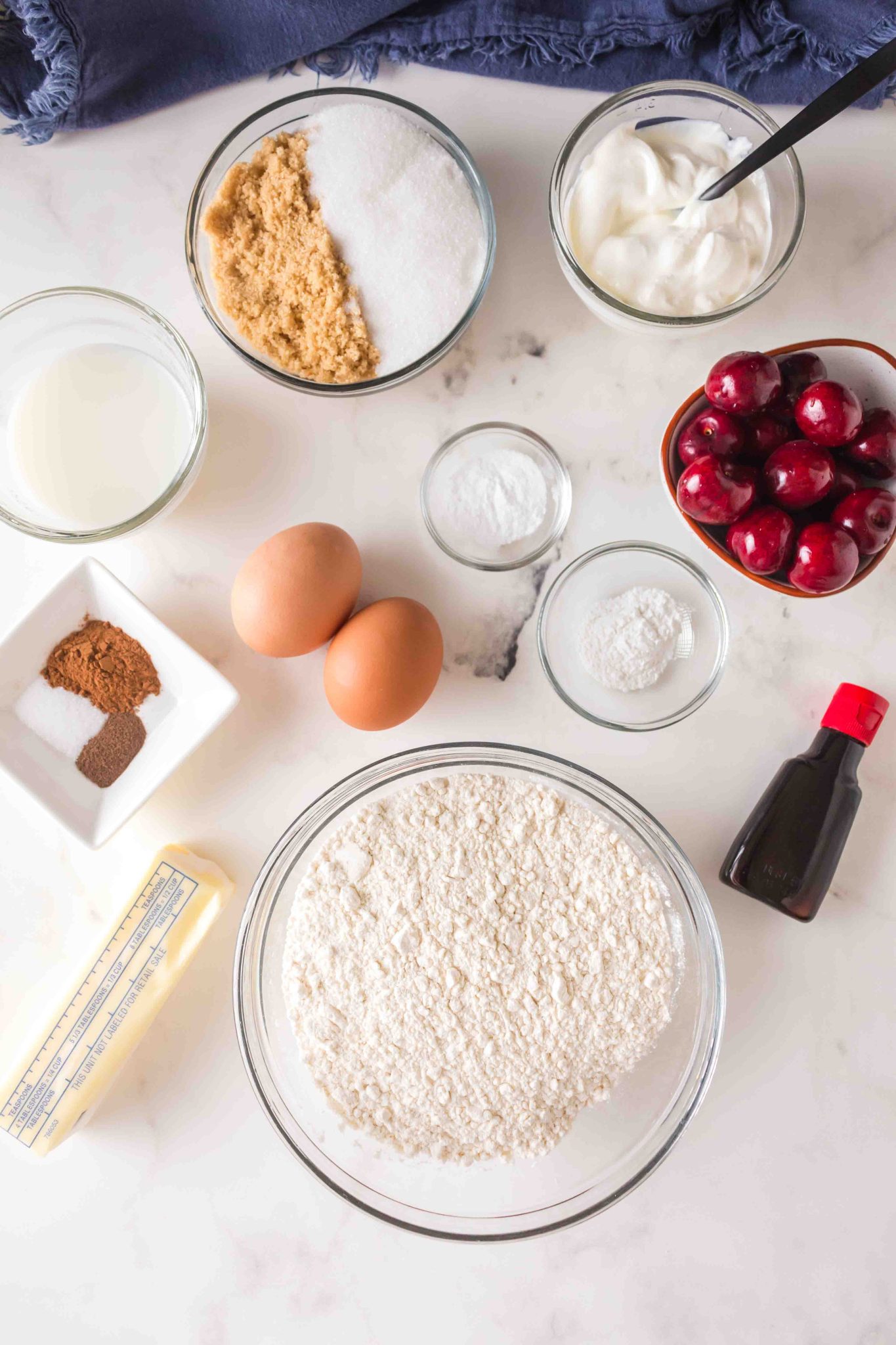 Ingredients used to make homemade cherry muffins including sugar, brown sugar, salt, baking soda, baking powder, eggs, all spice, vanilla, cherries, flour, butter, cinnamon, milk. - Hostess At Heart