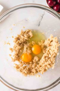 Top down view of a mixing bowl with eggs added to a mixture of creamed butter and sugar.