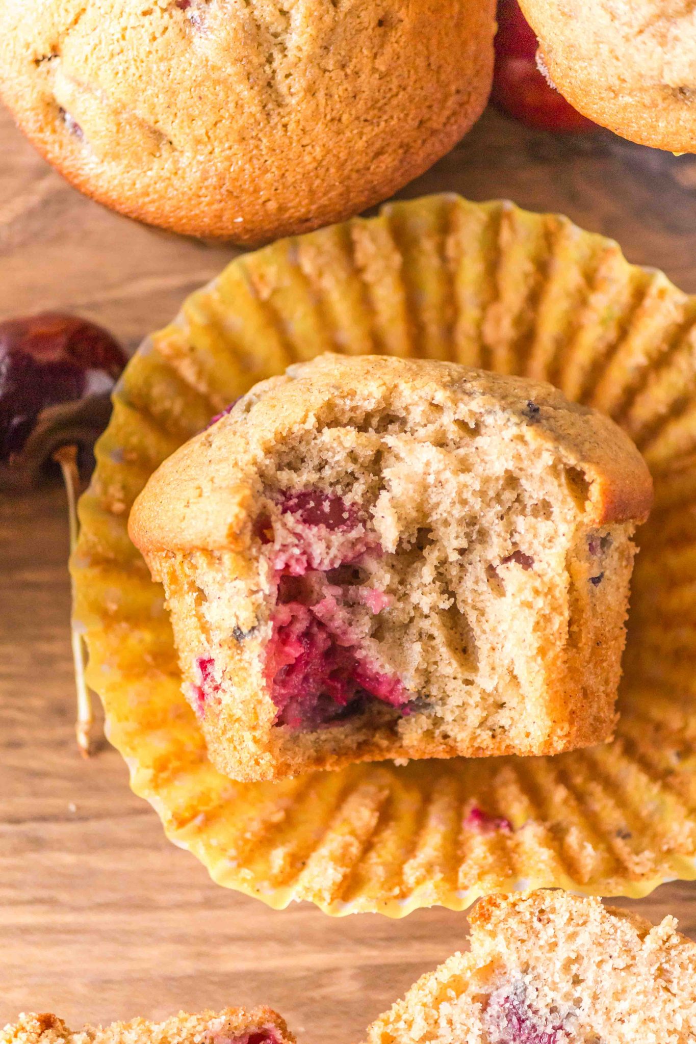 Top down view of a cherry muffin with a bite taken out of it showing fresh cherries.