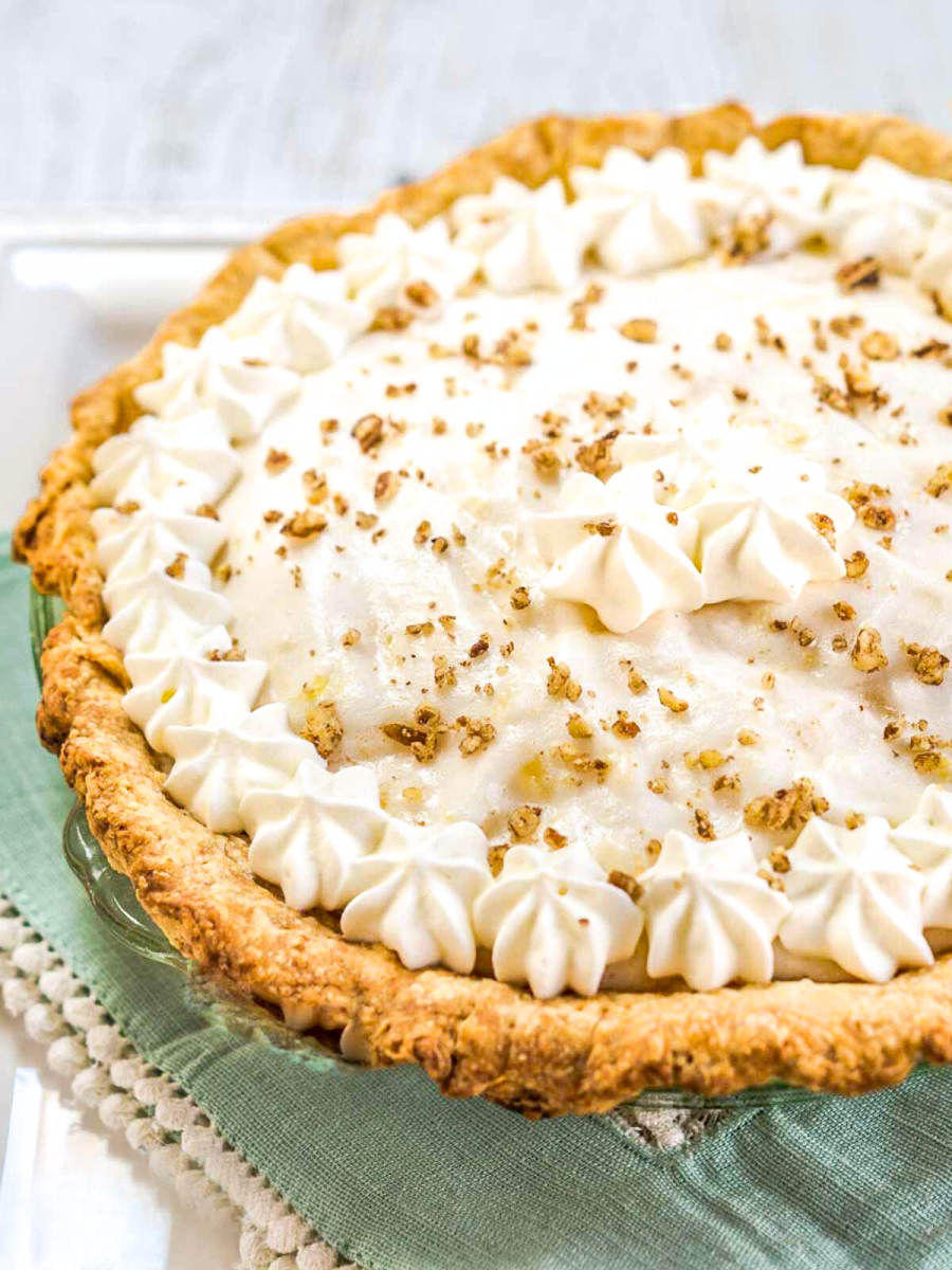 Sideview of three quarters of a angel food pie topped with crushed nuts and whipped cream stars - Hostess At Heart