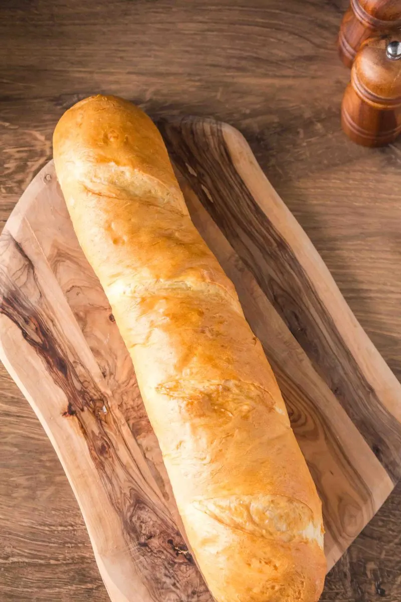 A scored baguette baked golden brown sitting on a cutting board - Hostess At Heart