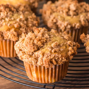 Tableview image of a cinnamon peach muffin topped with streusel sitting on a cooling rack. Hostess At Heart
