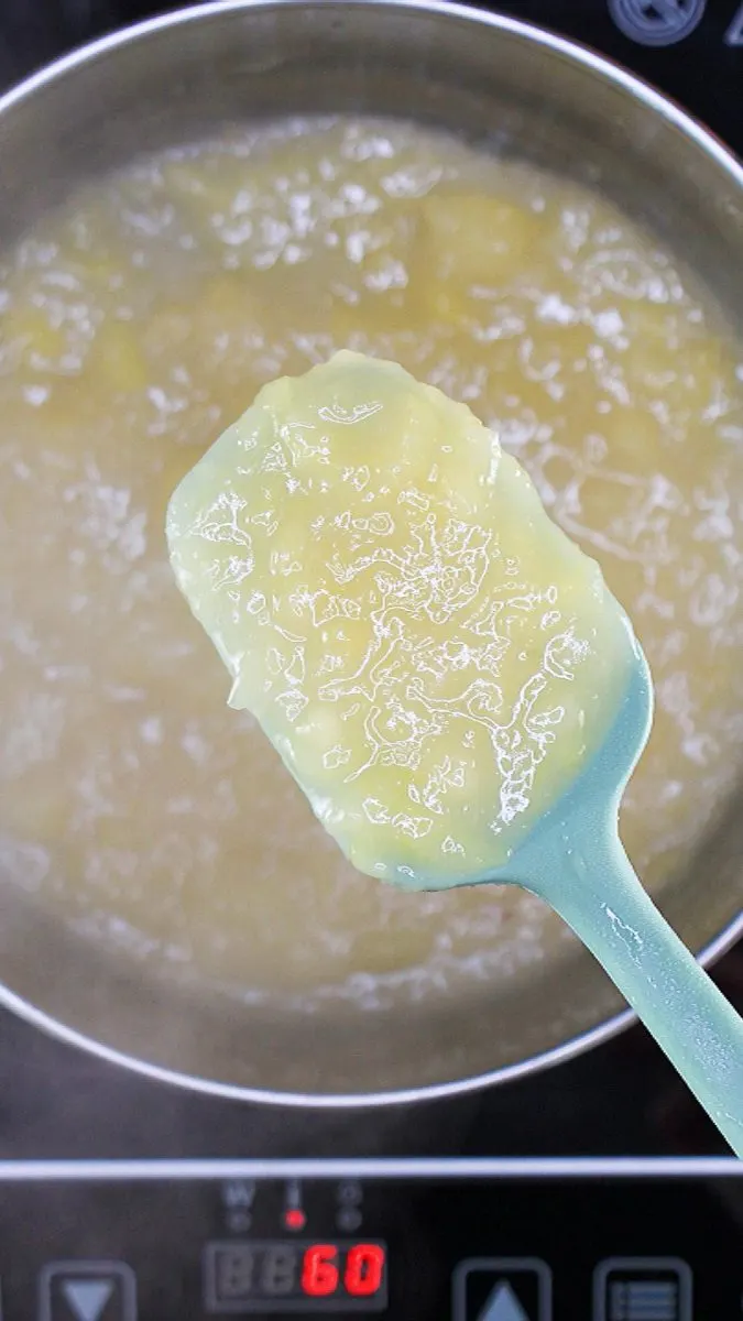 A spatula filled with pineapple pie filling after thickened in a saucepan - Hostess At Heart