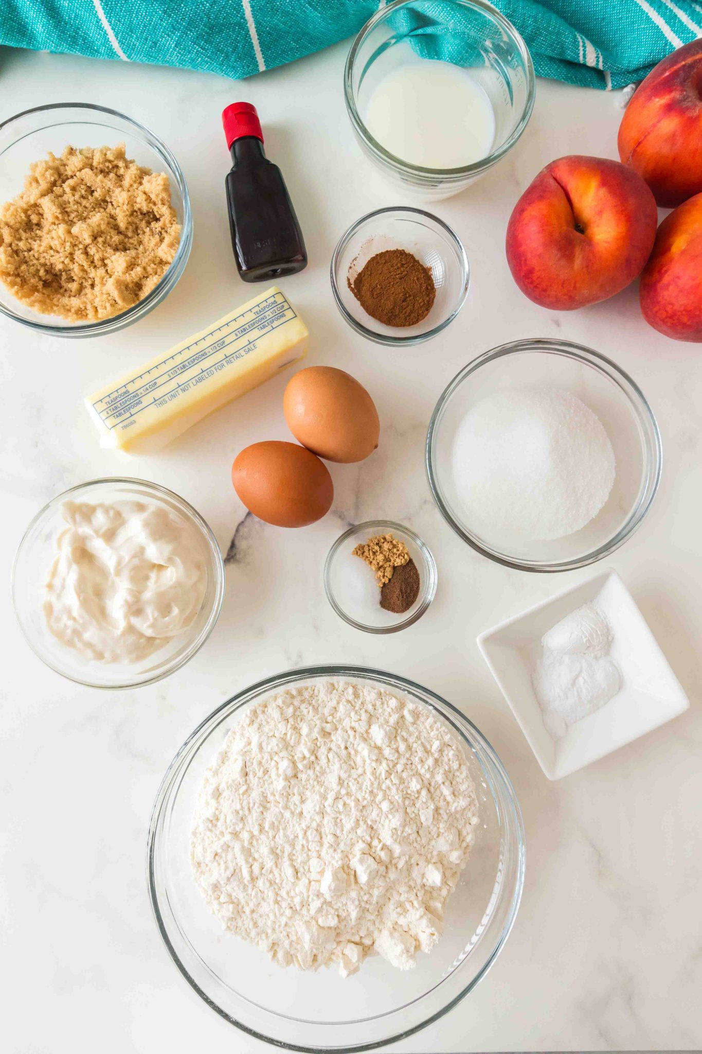 Ingredients for peach muffins: butter, brown sugar, white sugar, eggs, greek yogurt, vanilla extract, all-purpose flour, baking soda, baking powder, ground cinnamon, salt, ground ginger, allspice, milk, and fresh peaches. - Hostess At Heart