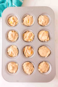 Top down view of a muffin tin filled with peach muffin batter - Hostess At Heart